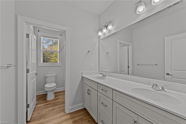 bathroom with toilet, vanity, and hardwood / wood-style floors