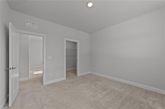 unfurnished bedroom featuring light colored carpet, a closet, and a walk in closet