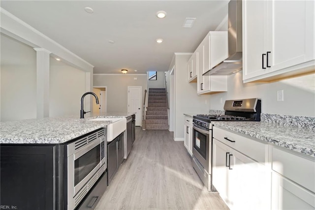 kitchen with white cabinetry, stainless steel appliances, a kitchen island with sink, and wall chimney exhaust hood