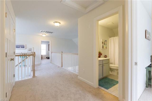 hallway with light colored carpet and crown molding