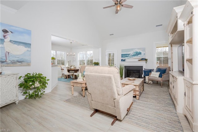 living room with ceiling fan with notable chandelier and light hardwood / wood-style flooring