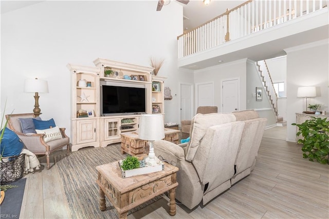 living room featuring hardwood / wood-style floors, a towering ceiling, ceiling fan, and ornamental molding