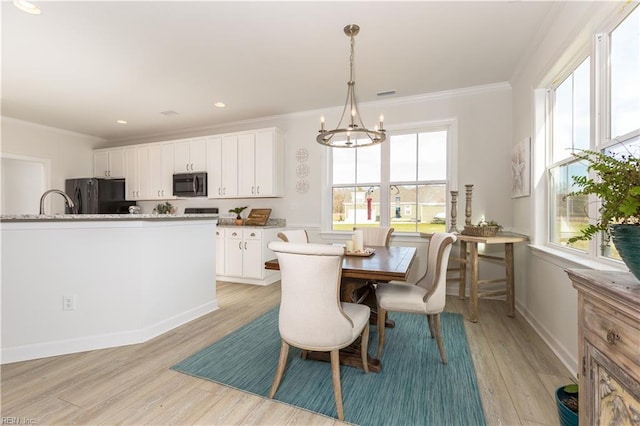 dining area featuring light wood-type flooring, crown molding, and a notable chandelier