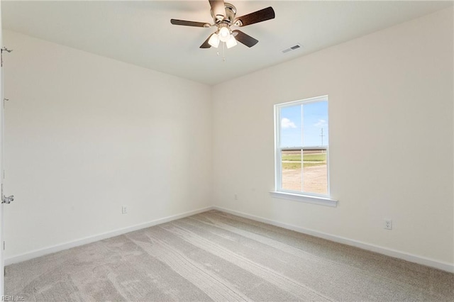 spare room featuring visible vents, light colored carpet, baseboards, and ceiling fan