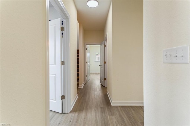 corridor featuring wood finished floors and baseboards