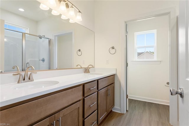 bathroom featuring a shower stall, wood finished floors, double vanity, and a sink