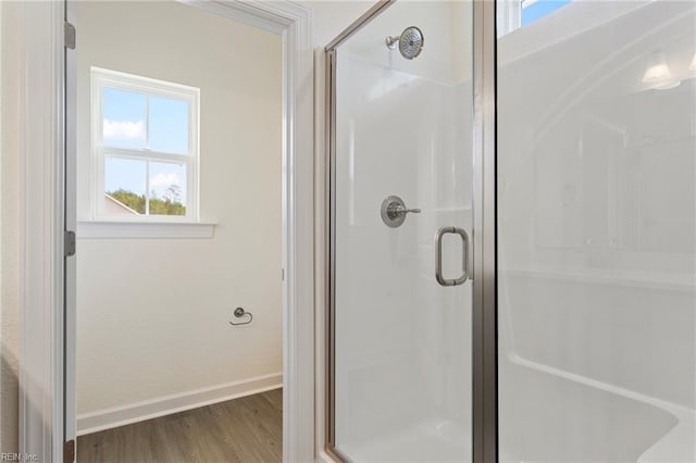 bathroom with a shower stall, wood finished floors, and baseboards