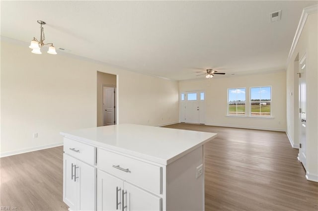 kitchen with a kitchen island, hanging light fixtures, crown molding, ceiling fan with notable chandelier, and light wood-type flooring