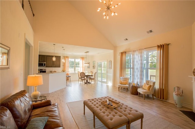 living room featuring high vaulted ceiling, light hardwood / wood-style flooring, and a notable chandelier