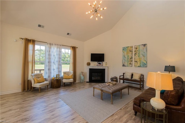 living room with light hardwood / wood-style floors, a chandelier, and high vaulted ceiling