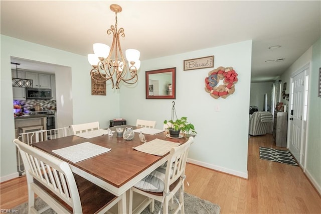 dining area featuring light hardwood / wood-style flooring and a chandelier