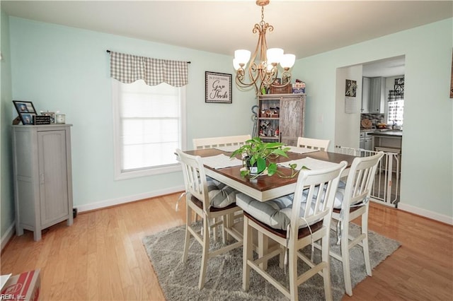 dining space with light hardwood / wood-style floors and a chandelier