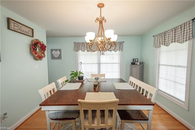 dining space with light hardwood / wood-style floors and a notable chandelier