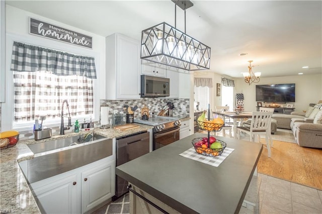 kitchen with light stone counters, white cabinetry, appliances with stainless steel finishes, pendant lighting, and light hardwood / wood-style flooring