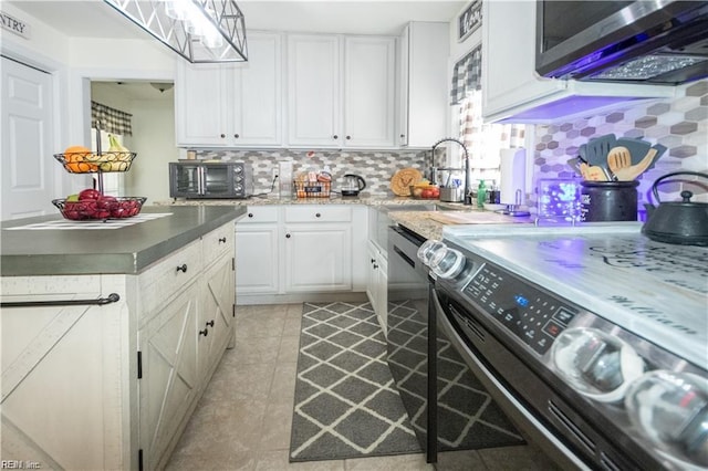 kitchen featuring backsplash, appliances with stainless steel finishes, light tile patterned floors, pendant lighting, and white cabinets