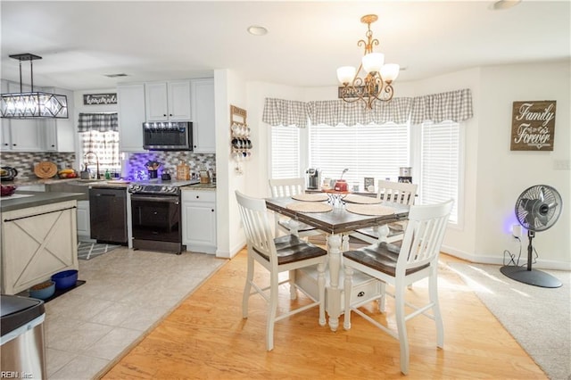 dining area featuring sink, a notable chandelier, and light hardwood / wood-style flooring