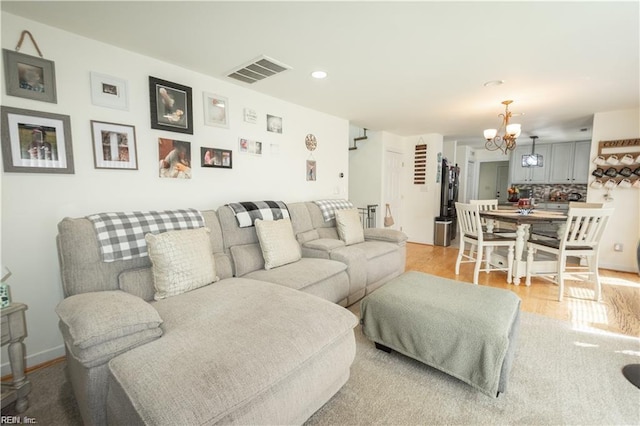 living room with light hardwood / wood-style floors and an inviting chandelier