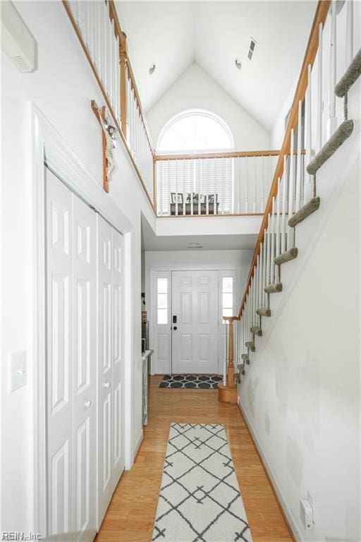 entrance foyer with light wood-type flooring and high vaulted ceiling