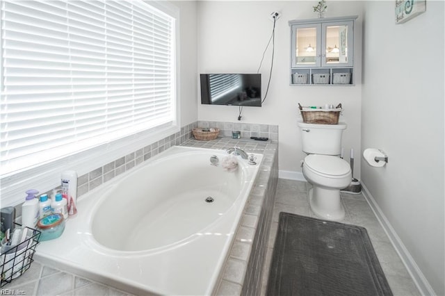 bathroom featuring toilet, a relaxing tiled tub, tile patterned flooring, and a healthy amount of sunlight