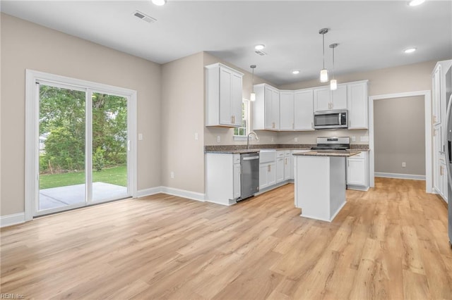 kitchen with stainless steel appliances, light hardwood / wood-style floors, hanging light fixtures, and white cabinetry