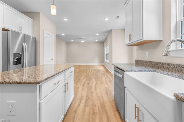 kitchen featuring white cabinetry, light stone counters, appliances with stainless steel finishes, hanging light fixtures, and light hardwood / wood-style flooring