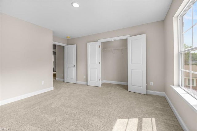 unfurnished bedroom featuring a closet and light colored carpet