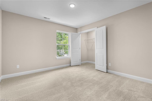 unfurnished bedroom with light colored carpet and a closet