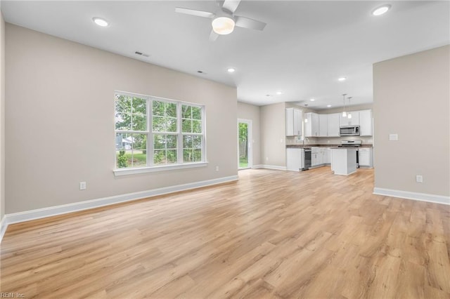 unfurnished living room with ceiling fan and light hardwood / wood-style flooring