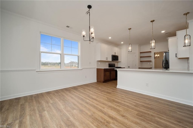 kitchen featuring ornamental molding, stainless steel appliances, white cabinetry, hanging light fixtures, and light hardwood / wood-style flooring