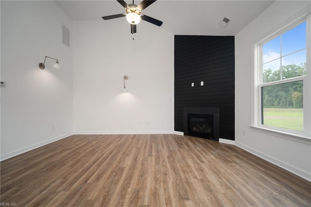 unfurnished living room with ceiling fan, wood-type flooring, and a large fireplace