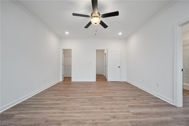 unfurnished bedroom with light hardwood / wood-style floors, a walk in closet, ceiling fan, and crown molding