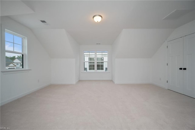 bonus room featuring light colored carpet, a healthy amount of sunlight, and vaulted ceiling