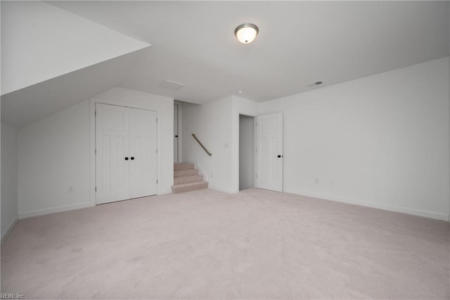 additional living space featuring lofted ceiling and light colored carpet