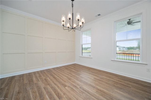 spare room featuring ornamental molding, hardwood / wood-style flooring, ceiling fan with notable chandelier, and a healthy amount of sunlight