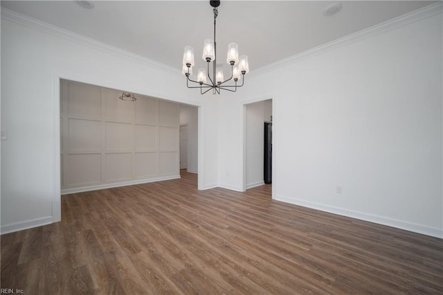 spare room featuring dark hardwood / wood-style floors, a notable chandelier, and ornamental molding