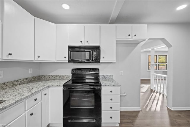 kitchen with light stone countertops, white cabinetry, and black appliances