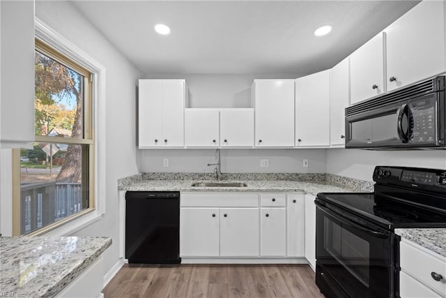 kitchen featuring white cabinetry, light wood-type flooring, and black appliances