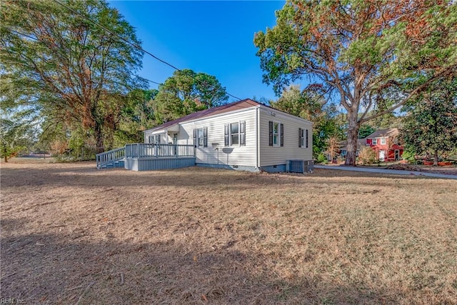 view of front of home with central AC unit, a front yard, and a deck