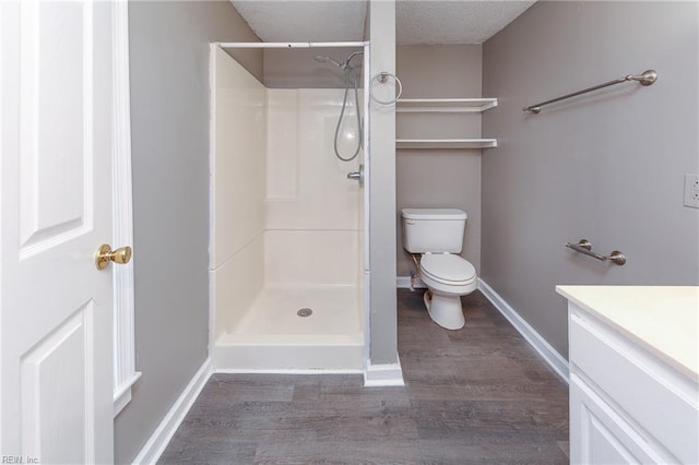 bathroom featuring vanity, a textured ceiling, hardwood / wood-style flooring, toilet, and a shower