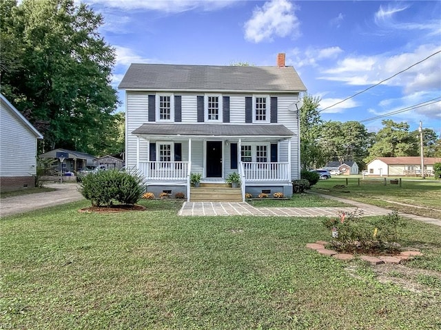 colonial inspired home featuring a porch and a front yard