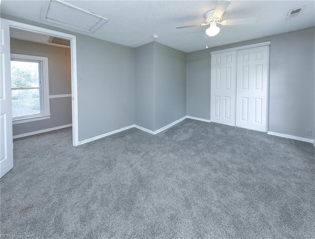 unfurnished bedroom featuring a closet, a textured ceiling, dark colored carpet, and ceiling fan