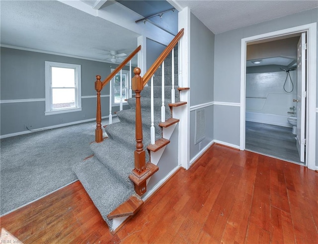 stairs with a textured ceiling, hardwood / wood-style flooring, and ceiling fan