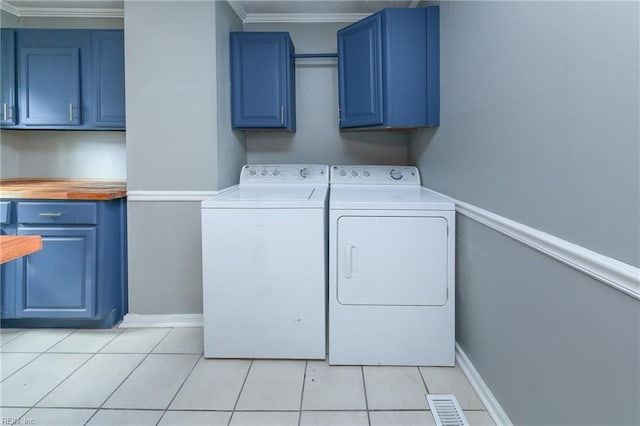 laundry room featuring cabinets, crown molding, independent washer and dryer, and light tile patterned floors