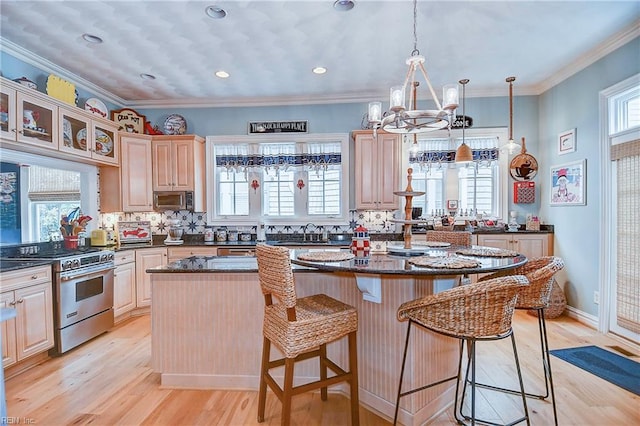 kitchen with crown molding, appliances with stainless steel finishes, light hardwood / wood-style floors, a chandelier, and a center island