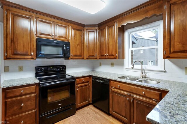 kitchen featuring sink, black appliances, tasteful backsplash, light stone countertops, and light wood-type flooring