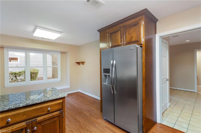 kitchen featuring light hardwood / wood-style floors, stainless steel fridge, and light stone countertops