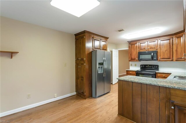 kitchen featuring kitchen peninsula, light hardwood / wood-style flooring, black appliances, and light stone countertops