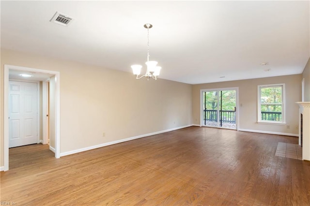 spare room with hardwood / wood-style flooring and a notable chandelier