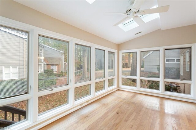 unfurnished sunroom with lofted ceiling with skylight, ceiling fan, and plenty of natural light