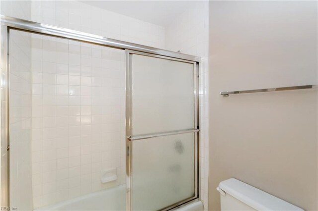 bathroom featuring bath / shower combo with glass door and toilet